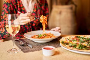 BEST Italian Restaurants in Branson Woman eats Italian pasta with tomato, meat. Close-up spaghetti Bolognese wind it around a fork with a spoon. Parmesan cheese