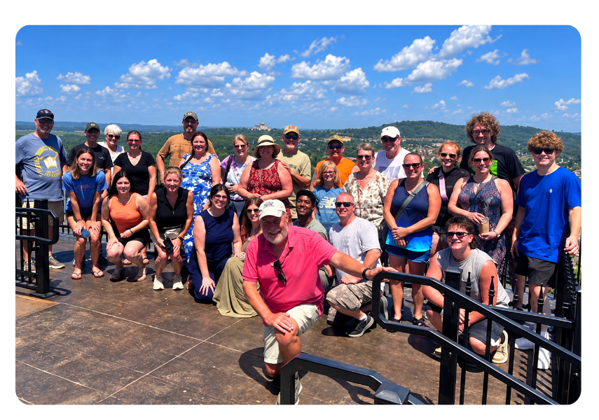 Gather Your Group 12 | Branson.com | Branson.com Group of about 25 people posing together on an outdoor overlook under a blue sky, smiling for a photo.