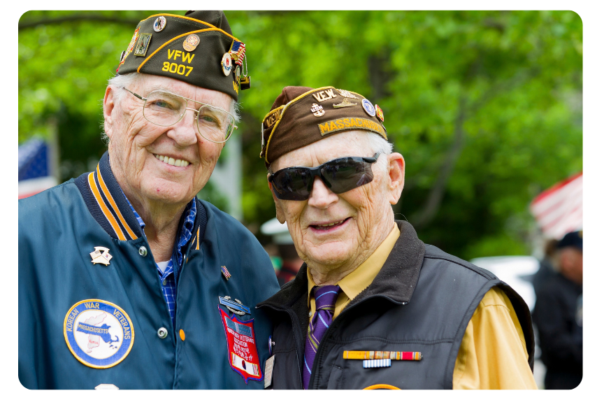 Gather Your Group 7 | Branson.com | Branson.com Two smiling veterans pose together outdoors, wearing VFW hats and vintage patches.